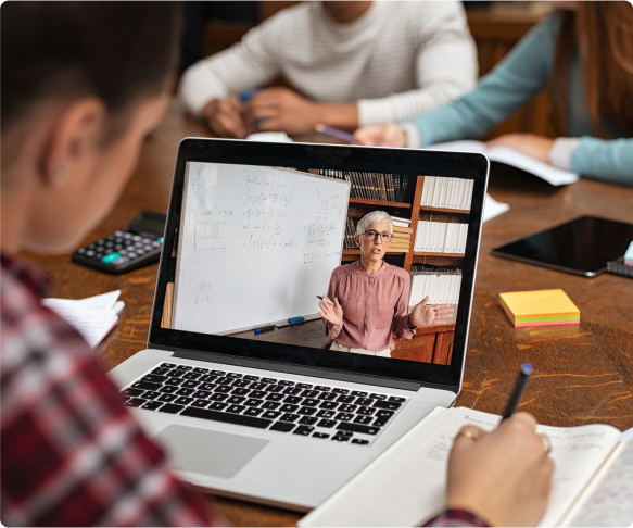 Eine Gruppe von Menschen berät sich mit der Studienberatung, während sie an einem Laptop sitzen.