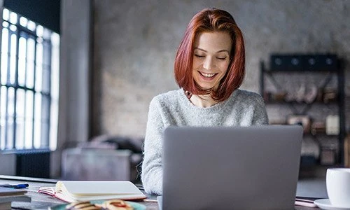 Eine Frau sitzt vor einem Laptop.