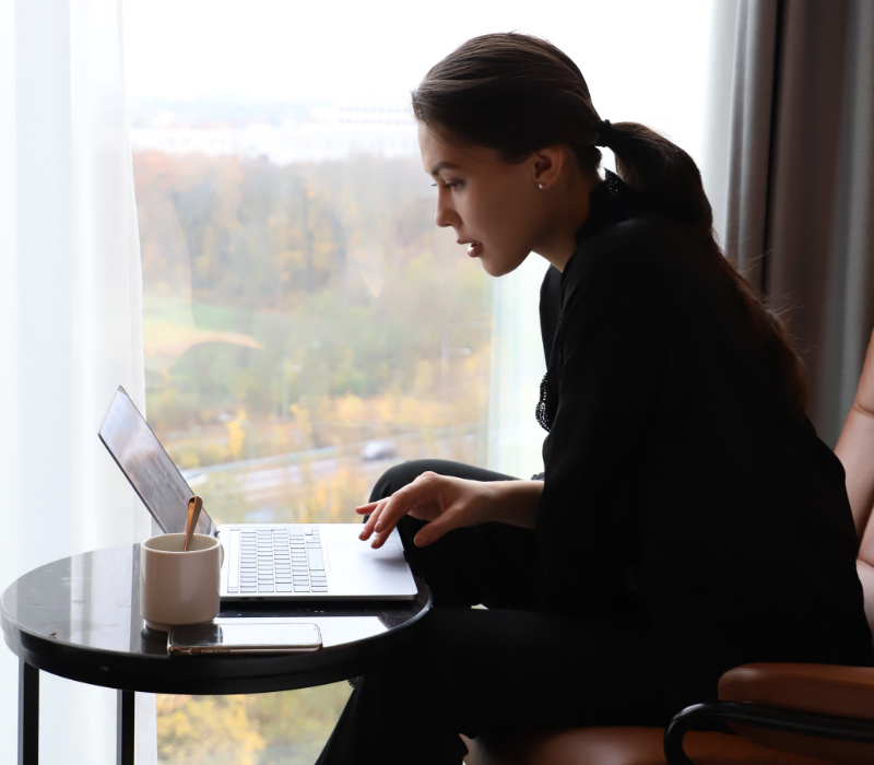 Eine Frau sitzt mit einem Laptop auf einem Stuhl.