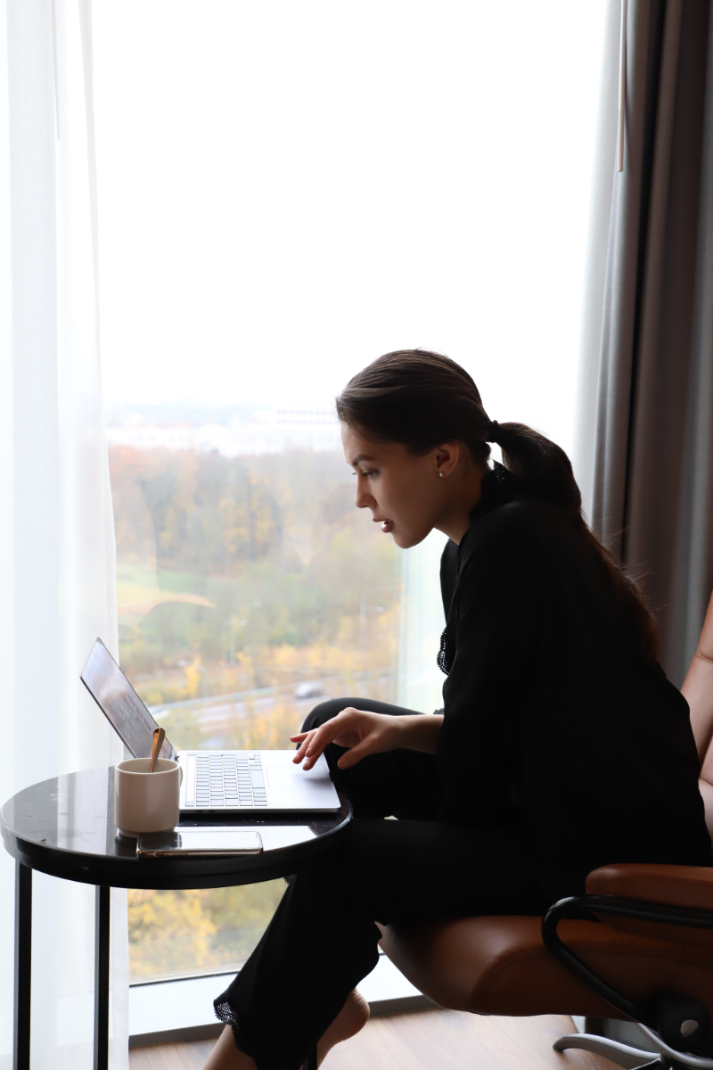 Eine Frau sitzt mit einem Laptop auf einem Stuhl.