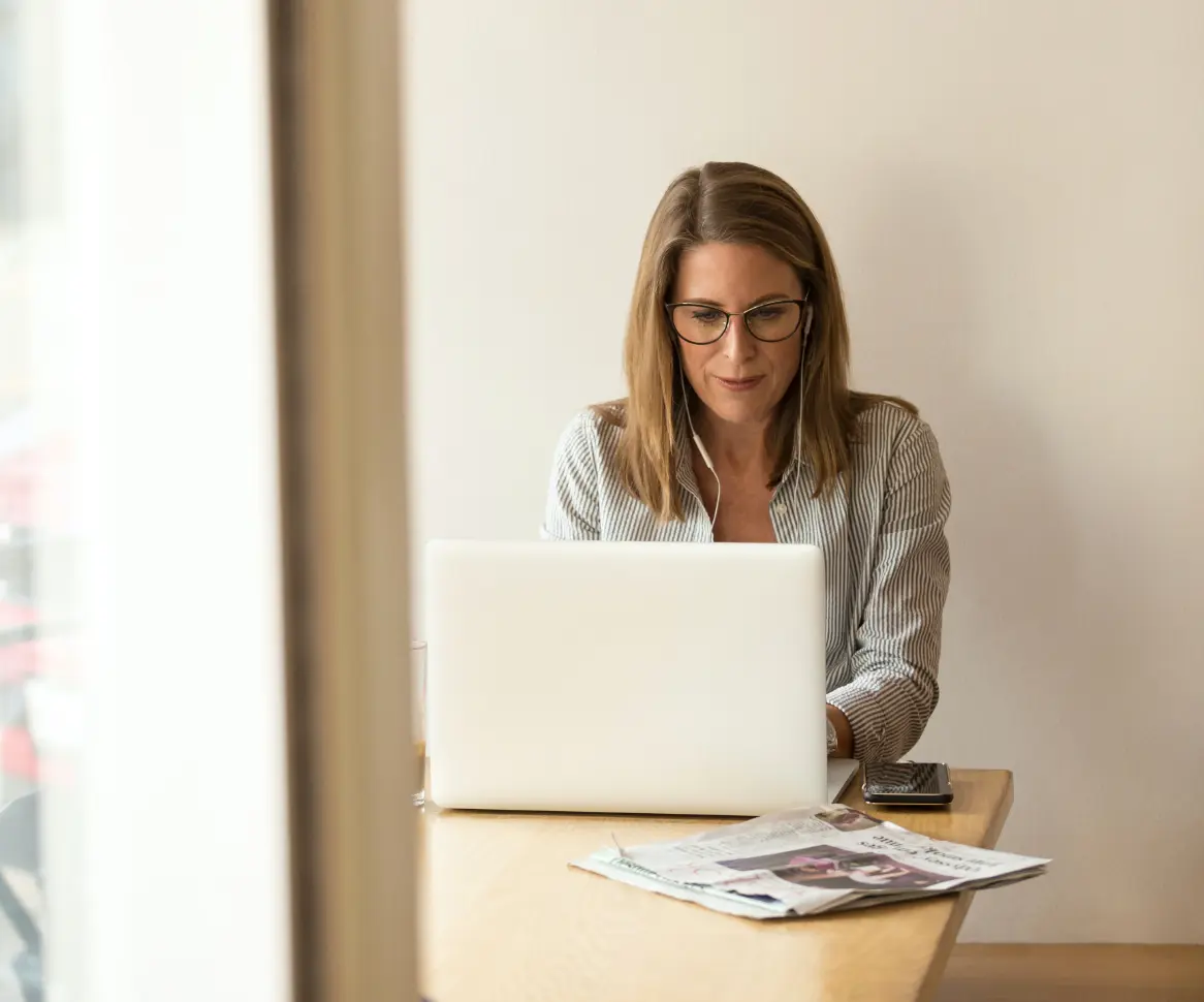 Eine Frau macht einen Sprachtest, während sie mit ihrem Laptop an einem Tisch sitzt.