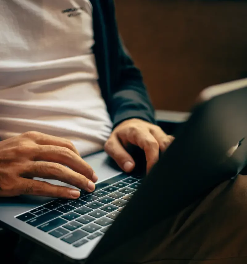Ein Mann sitzt auf einem Stuhl und benutzt einen Laptop.