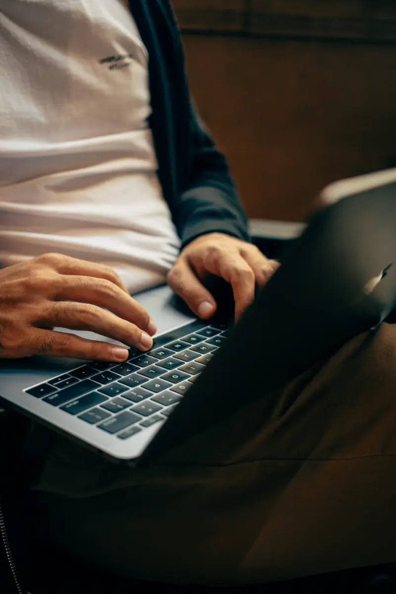 Ein Mann sitzt auf einem Stuhl und benutzt einen Laptop.