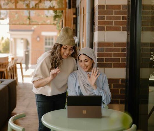 Zwei Frauen arbeiten in einem Café an einem Laptop.