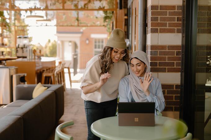 Zwei Frauen arbeiten in einem Café an einem Laptop.