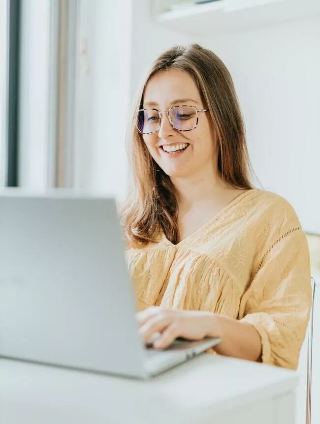 Eine Frau mit Brille benutzt zu Hause einen Laptop.