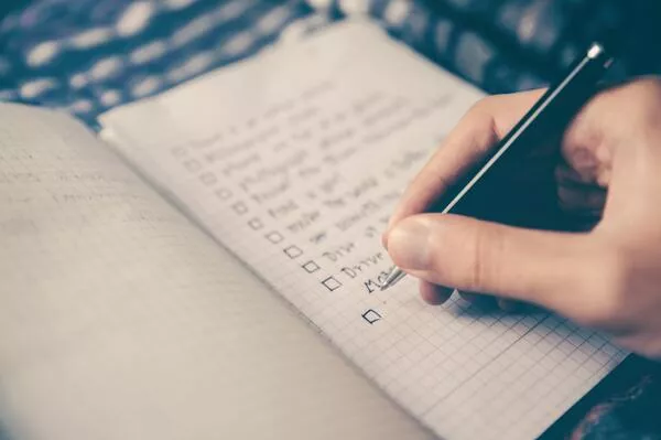Eine Person schreibt mit einem Stift auf ein Notizbuch.