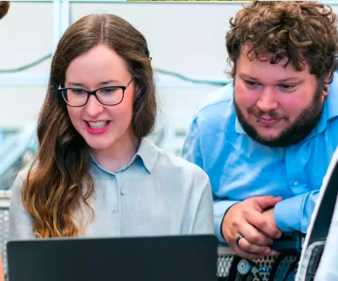 Studierende stehen vor einem PC und schauen auf den Bildschirm