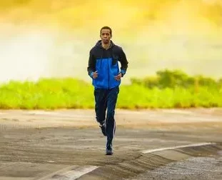 Mann joggt auf leerer Straße mit Landschaft im Hintergrund