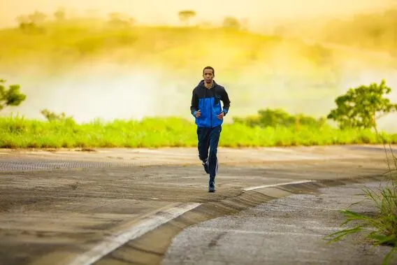 Mann joggt auf leerer Straße mit Landschaft im Hintergrund