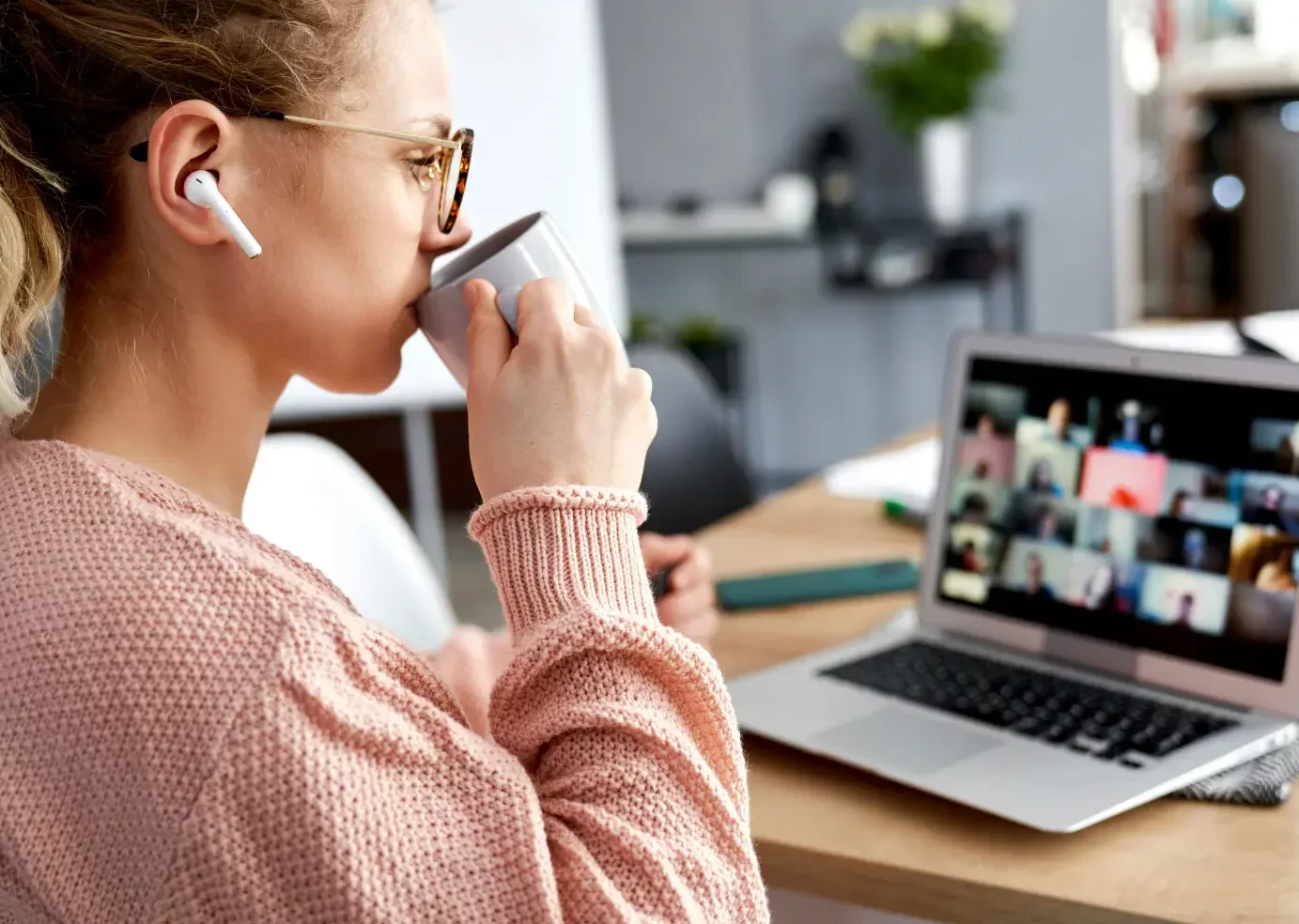 Frau sieht sich Webinar an und trinkt dabei Kaffee