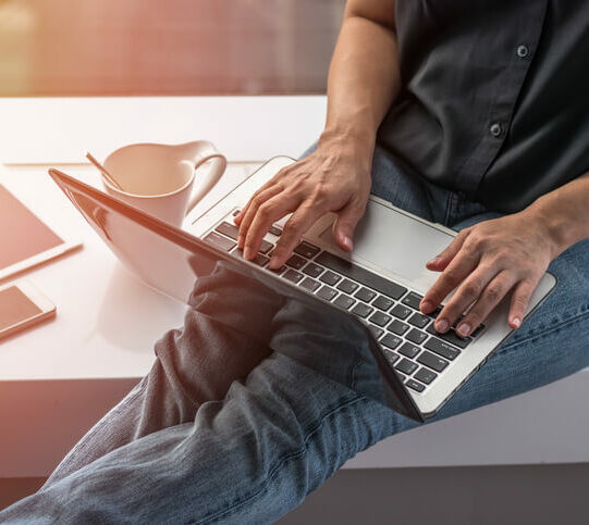 Student sitzt auf Bank und tippt etwas auf seinem Laptop
