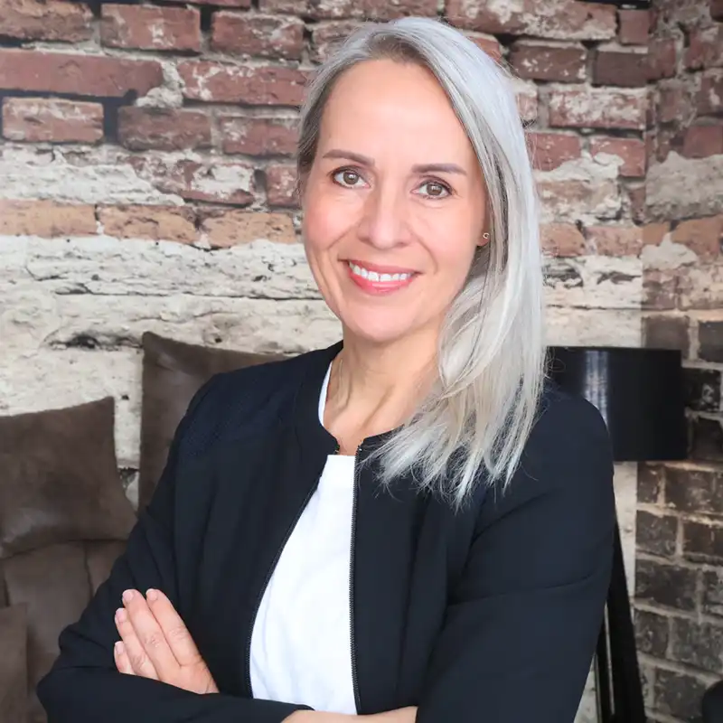 Kerstin Hendricks steht mit verschränkten Armen vor einer Mauer