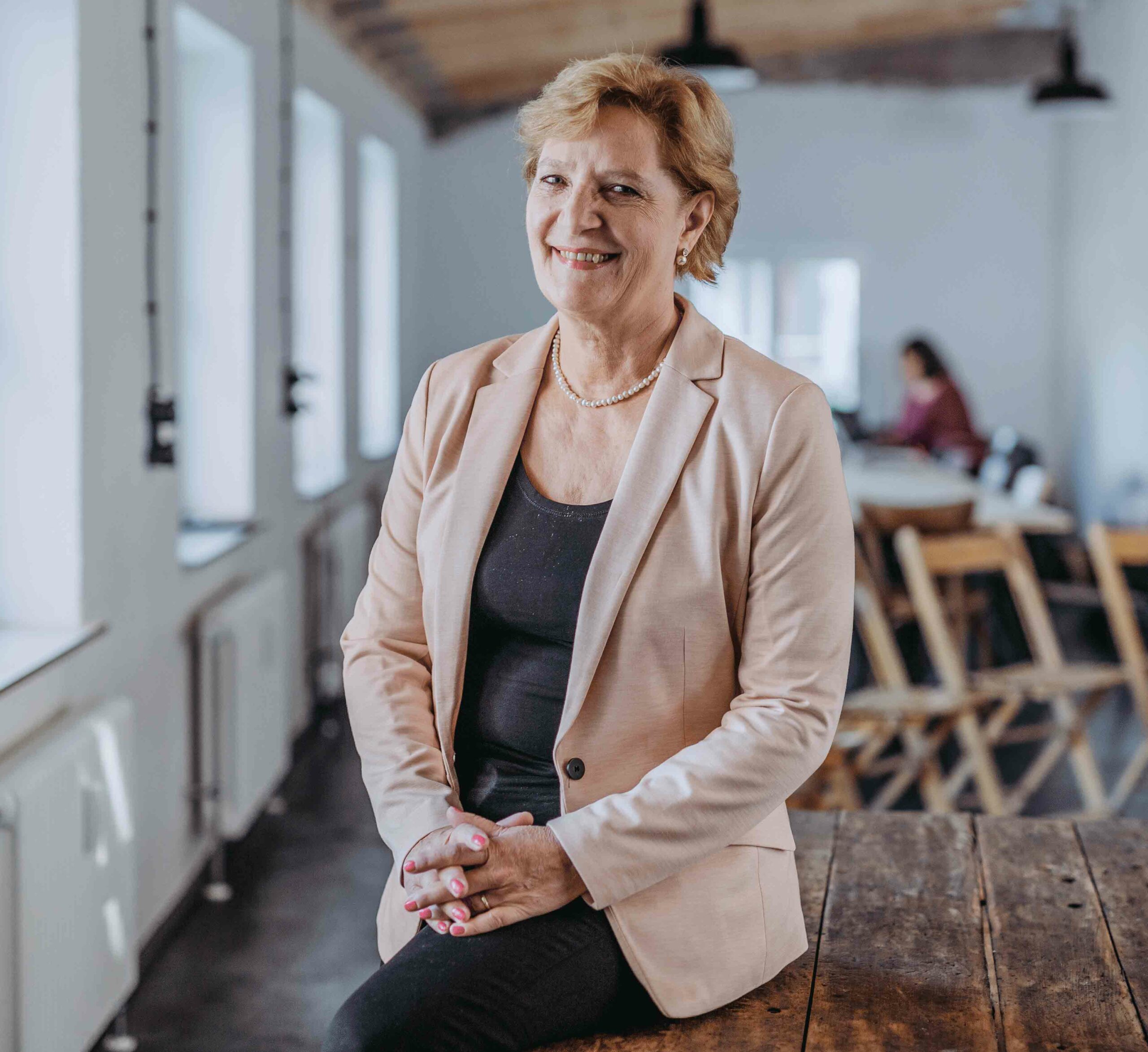 Prof. Dr. Brigitte Souveton-Reichel, sitzt auf einem Holztisch.