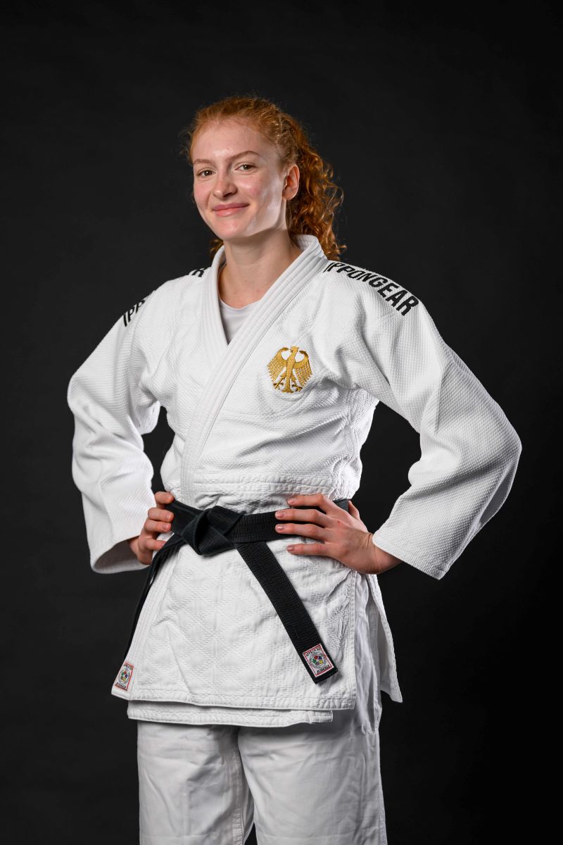 Samira-Bock, Judoka in weißem Judogi mit goldenem Bundesadler und schwarzem Gürtel vor schwarzem Hintergrund