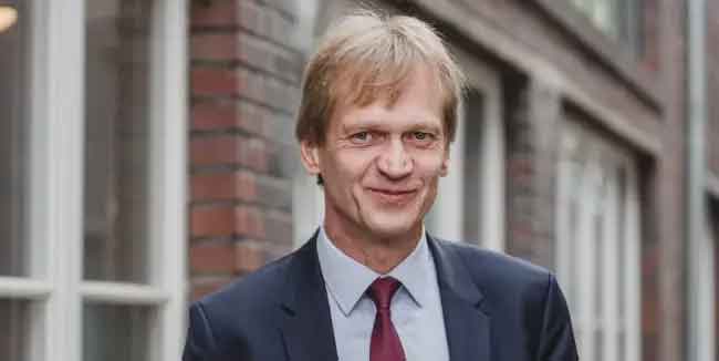 Prof. Dr. Matthias Riege im Anzug vor einem Backsteingebäude